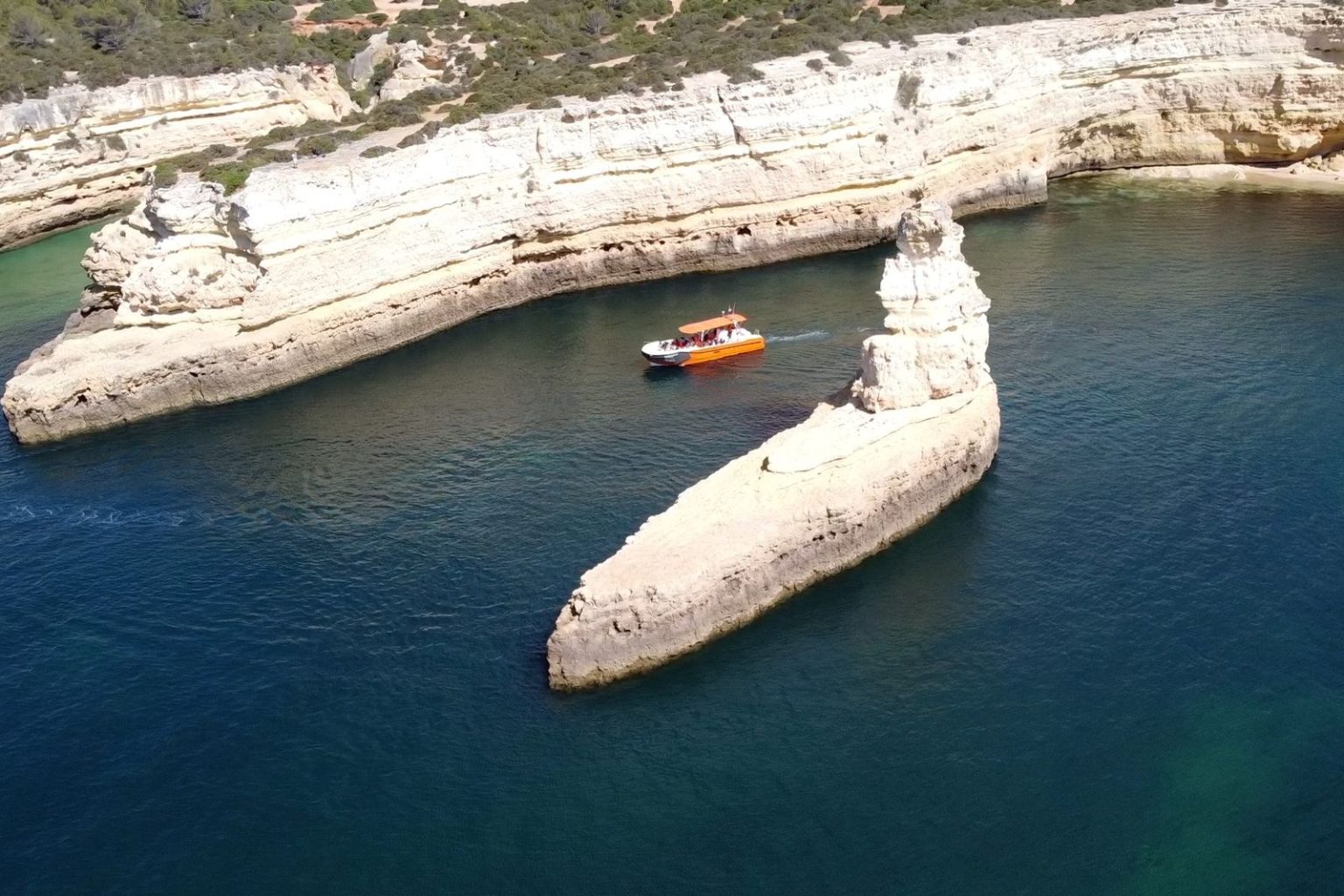 Boat sailing past white rock stacks