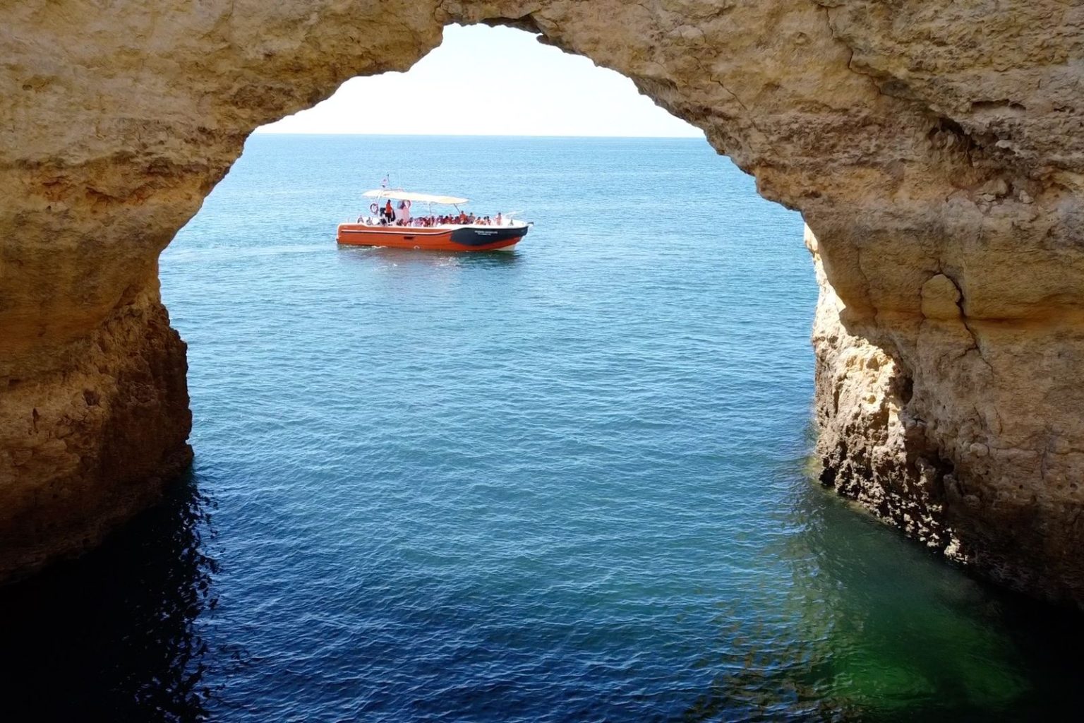 Boat seen through a natural sea arch