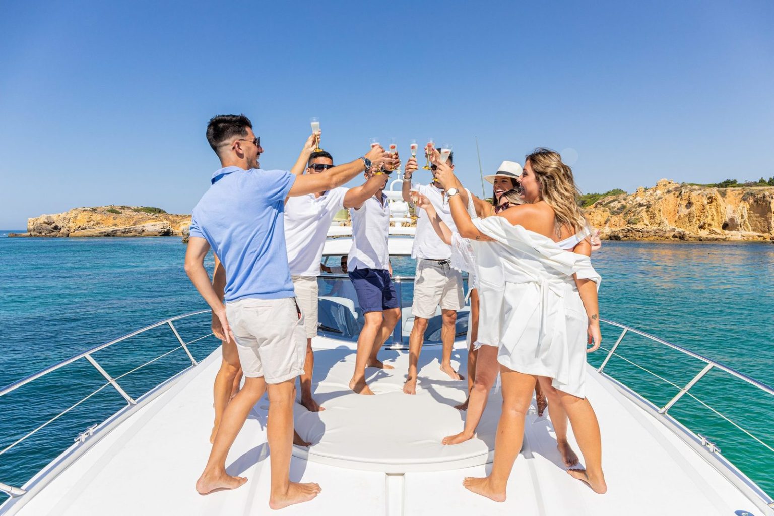 Grupo de amigos a brindar com champanhe na proa de um iate privado perto de Albufeira
