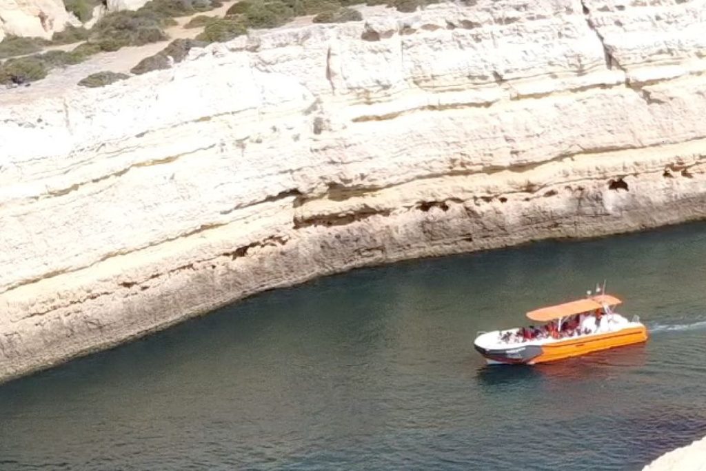 Cruise boat on turquoise water by the Algarve cliffs