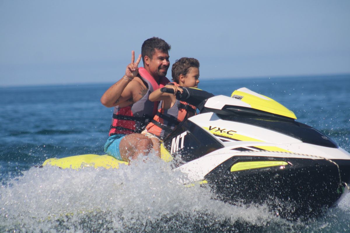 Adult and child riding a jet ski together with life jackets