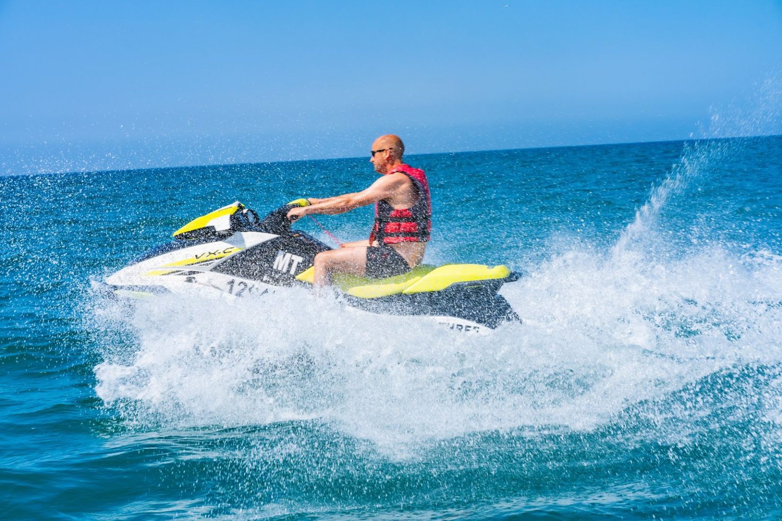 Rider on a jet ski throwing up spray on blue water