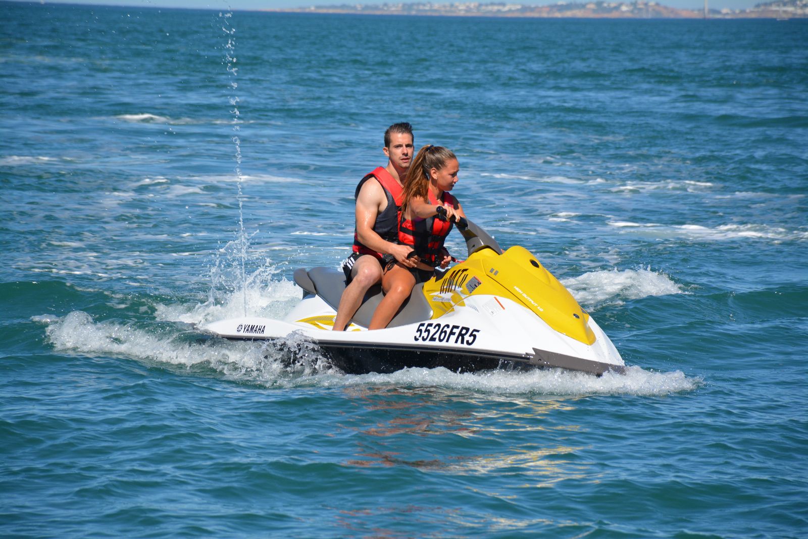 Two people riding one jet ski together
