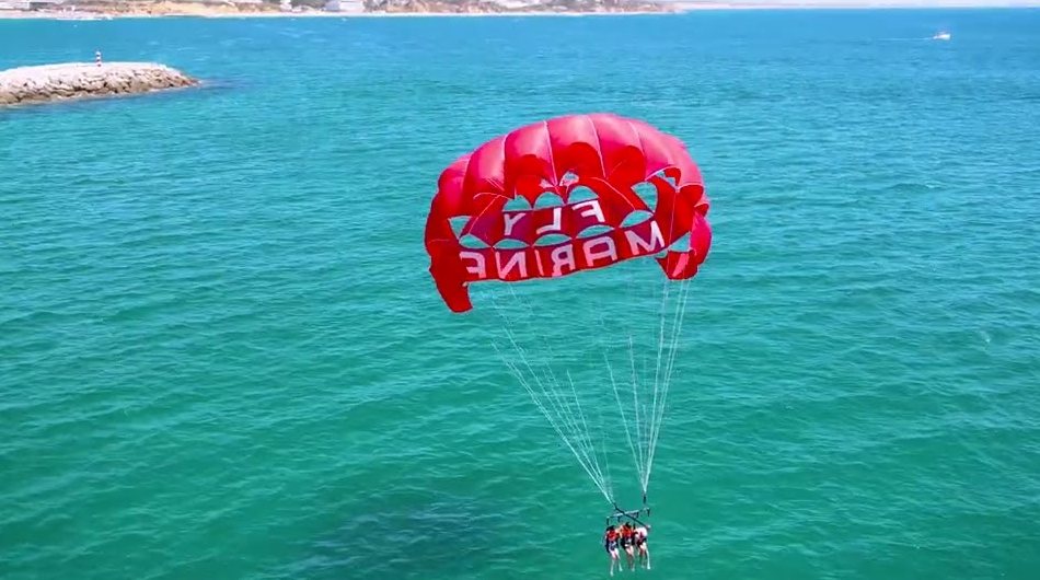 Vista aérea de pessoas a voar de parasailing sobre o mar em Albufeira