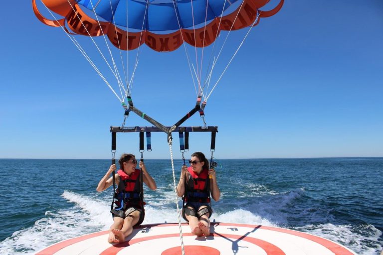 Two people on a tandem parasailing flight above the sea