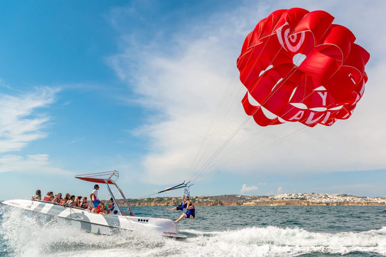 Pessoas a descolar da popa de um barco de parasailing no Algarve