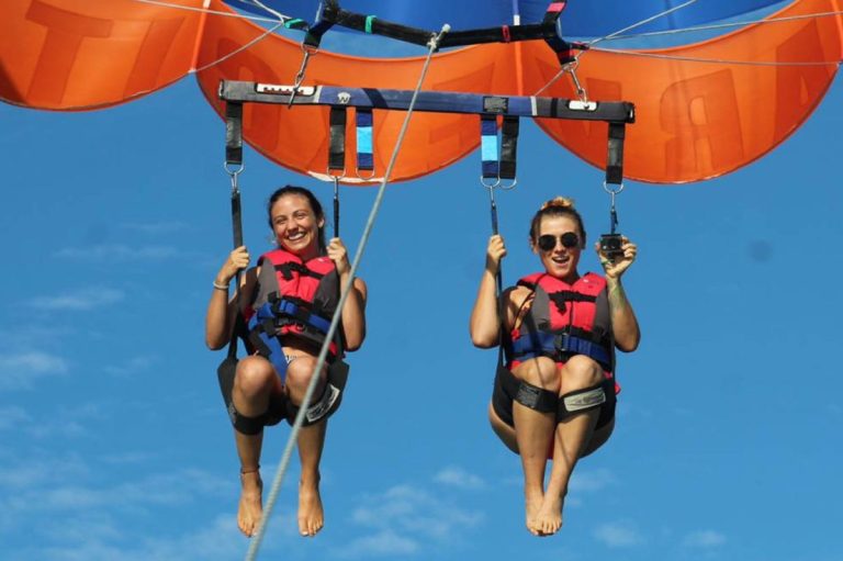 Two friends parasailing high above the sea on a tandem flight