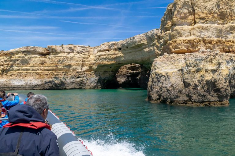 RIB boat passengers approaching a sea cave arch near Benagil