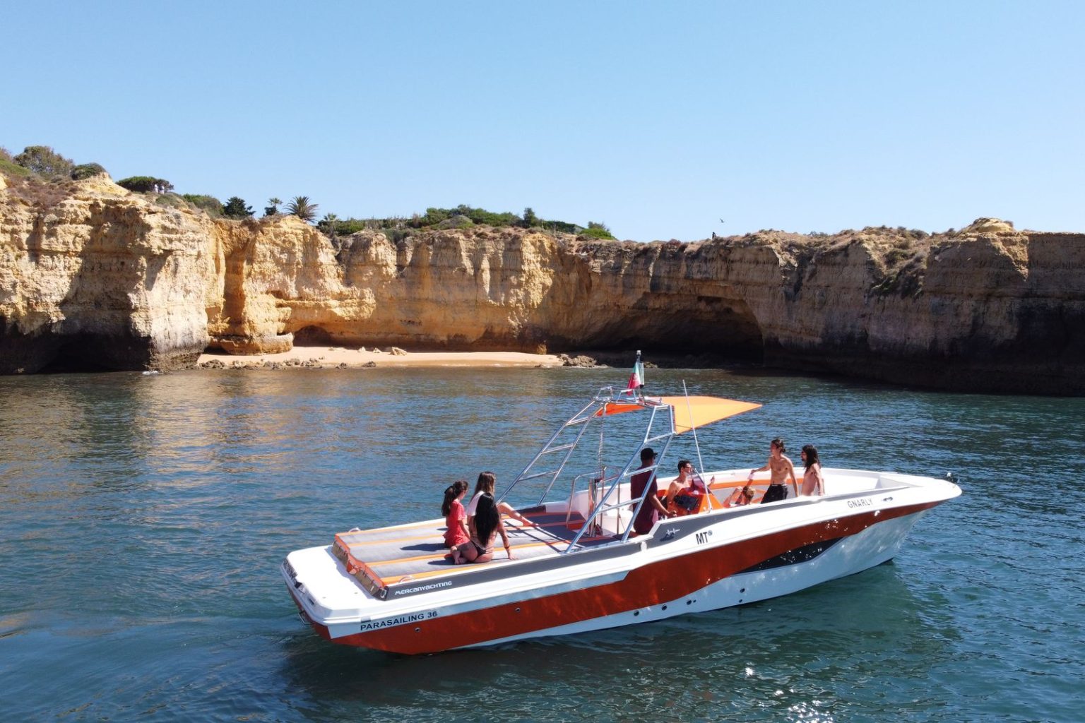 Private boat anchored by golden cliffs and a quiet beach