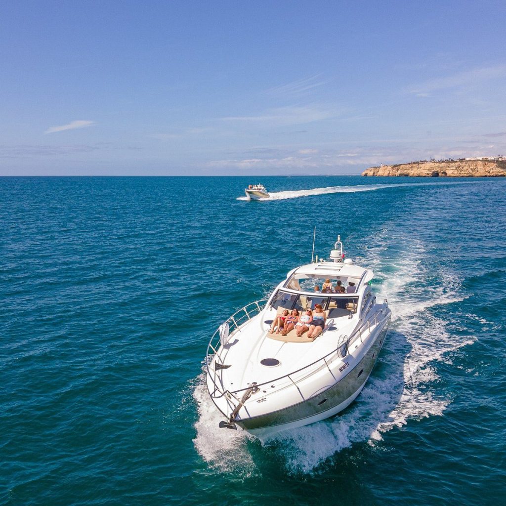 Convidados a apanhar sol na proa de um iate Sunseeker perto de Albufeira