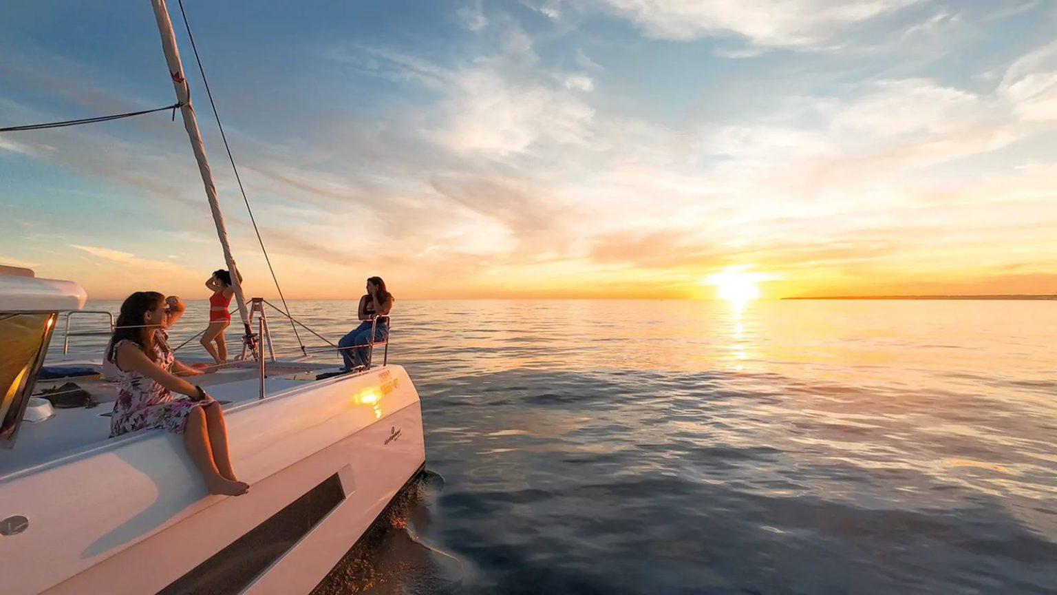 Guests watching the sunset from the bow of a sailing catamaran in the Algarve