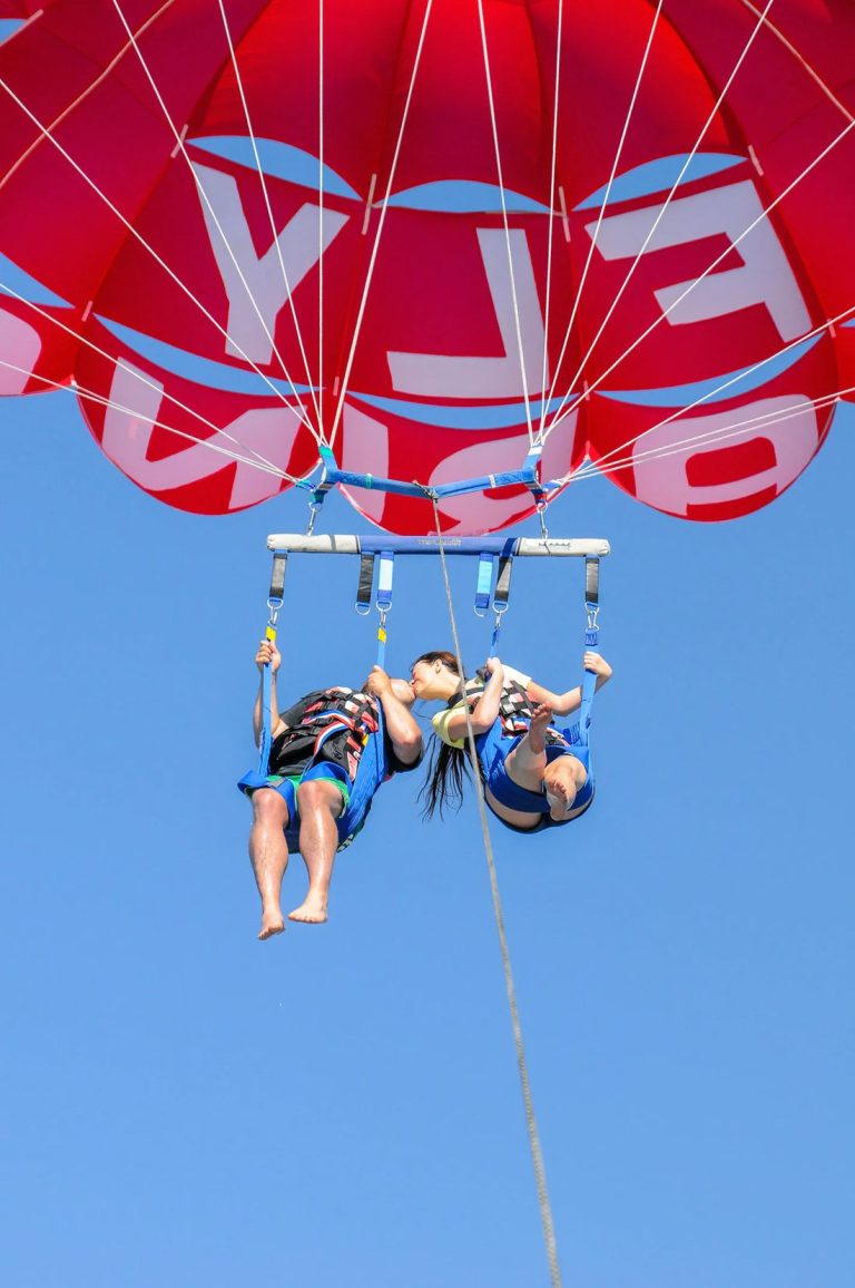 Couple flying a tandem parasail over the sea in Albufeira